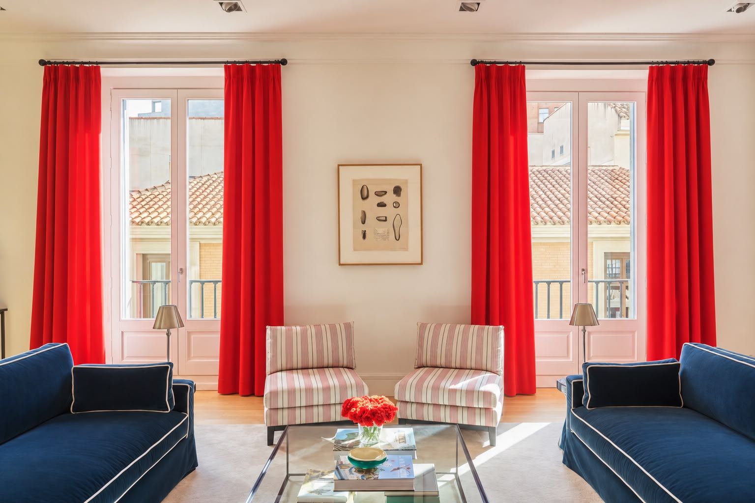 Two balconies framed by red velvet curtains, facing navy sofas