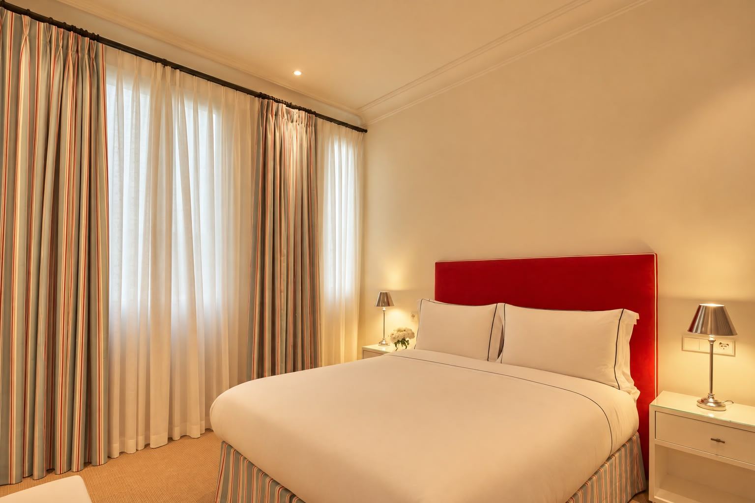 Double room with red velvet headboard and striped curtains