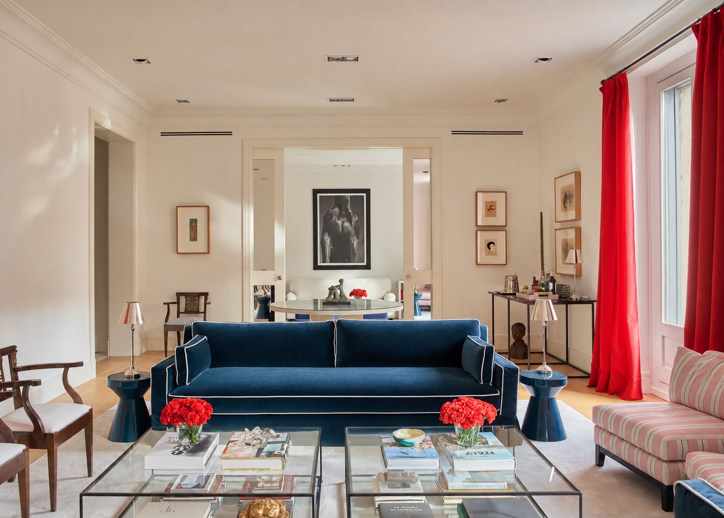 The living room: navy velvet sofa, glass tables and red carnations