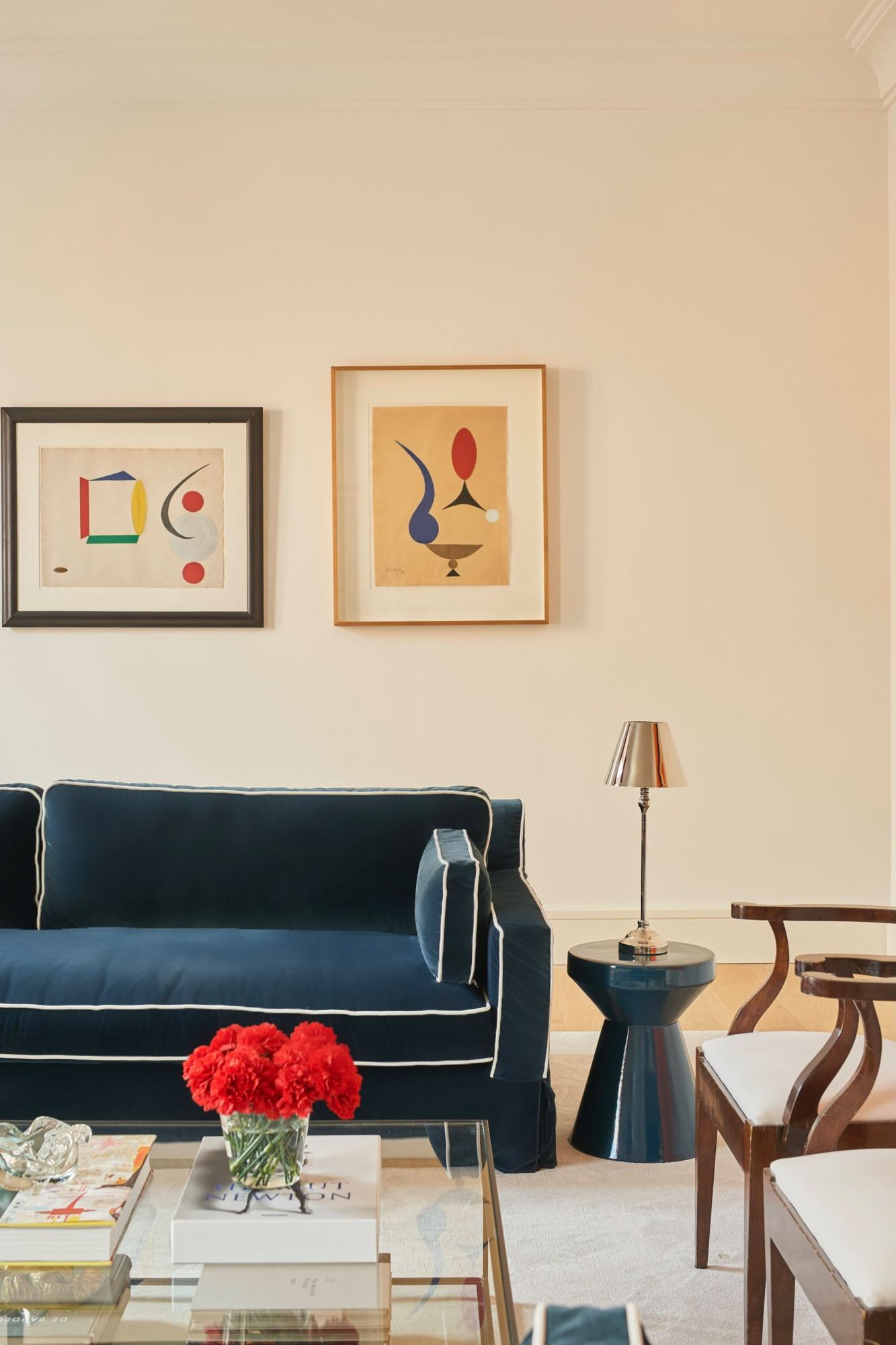 Abstract works on paper above the navy velvet sofa
