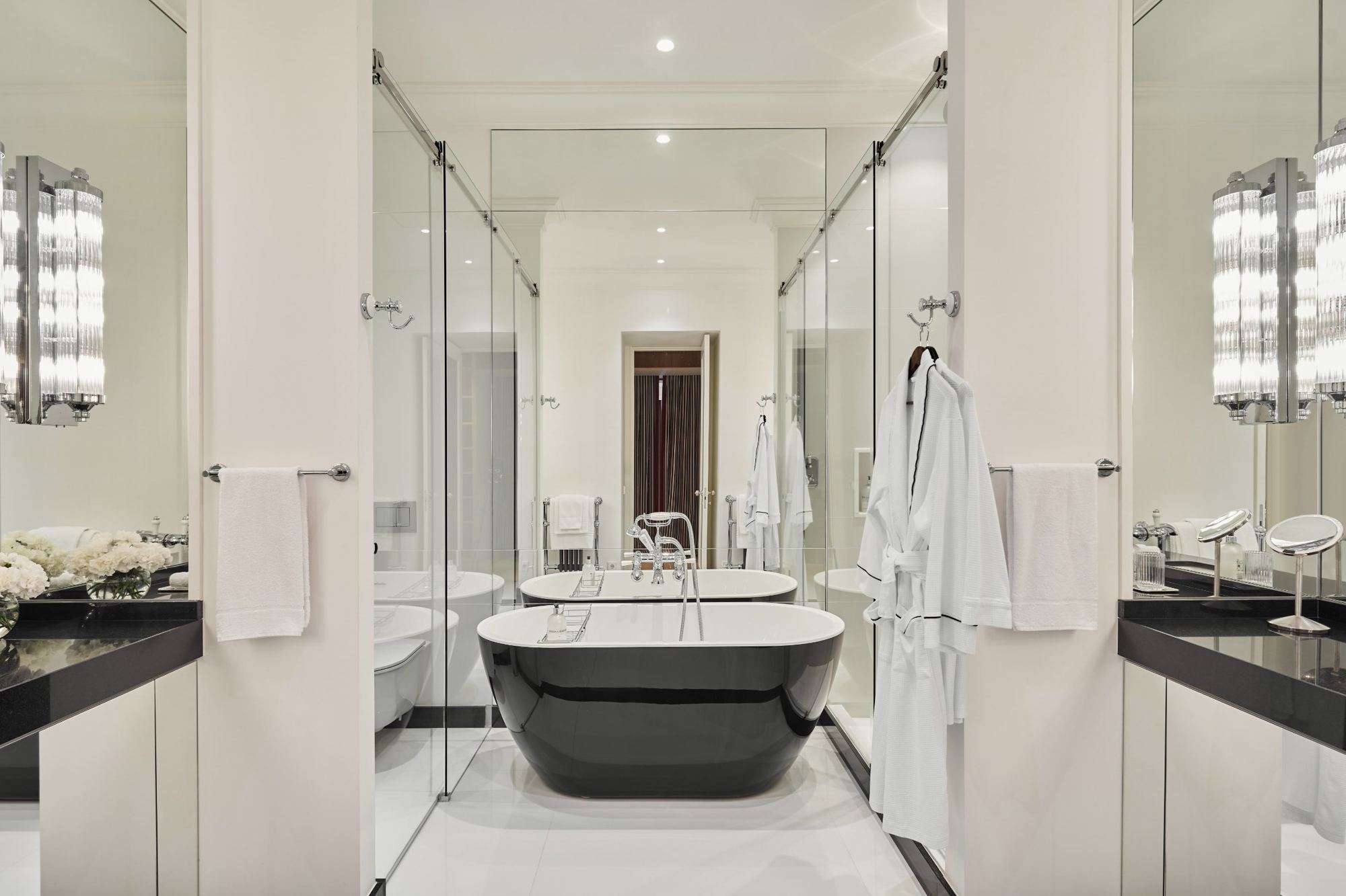 Master bath with black freestanding tub between glass showers