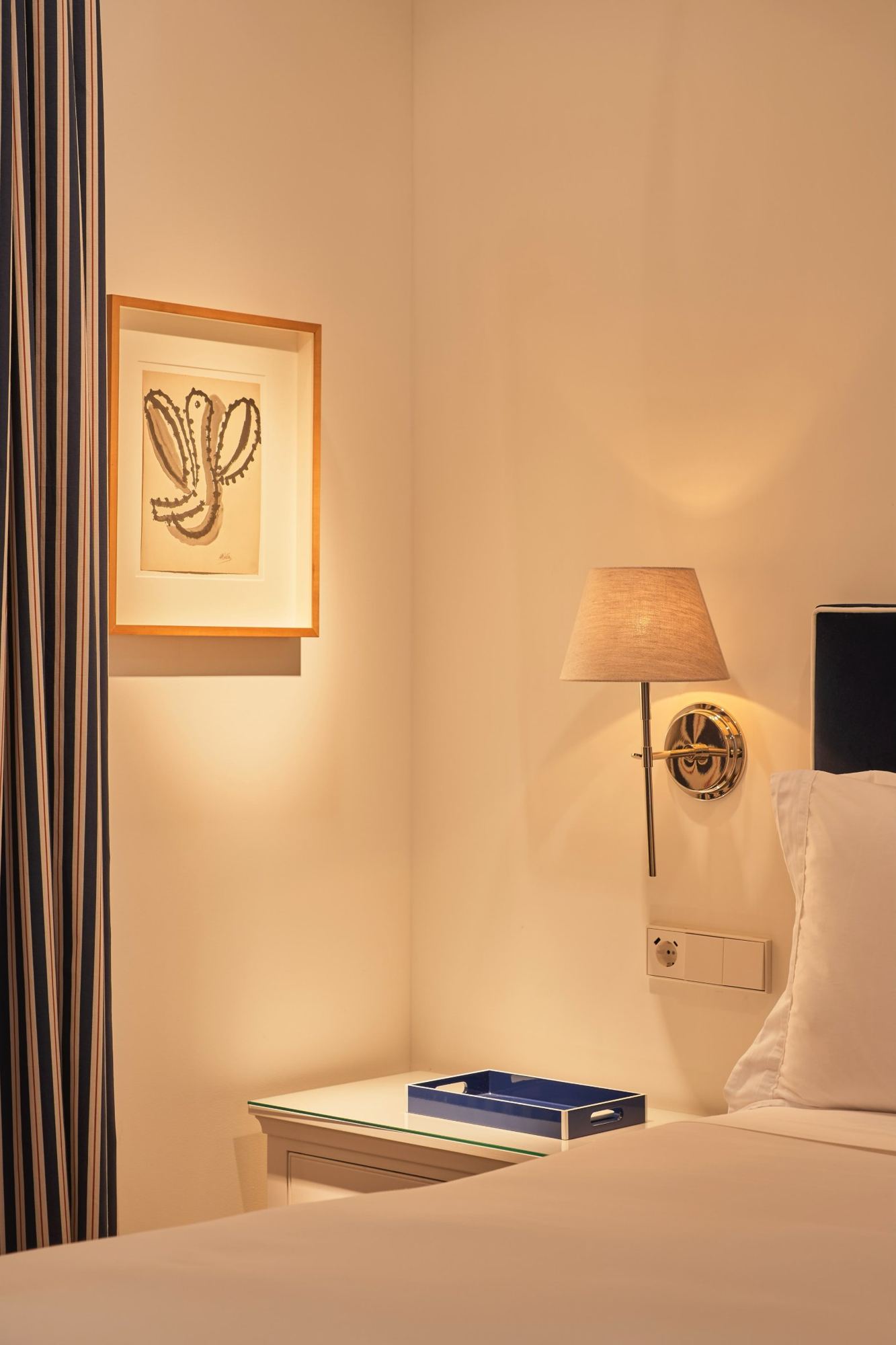 Bedside sconce and framed drawing in the master bedroom