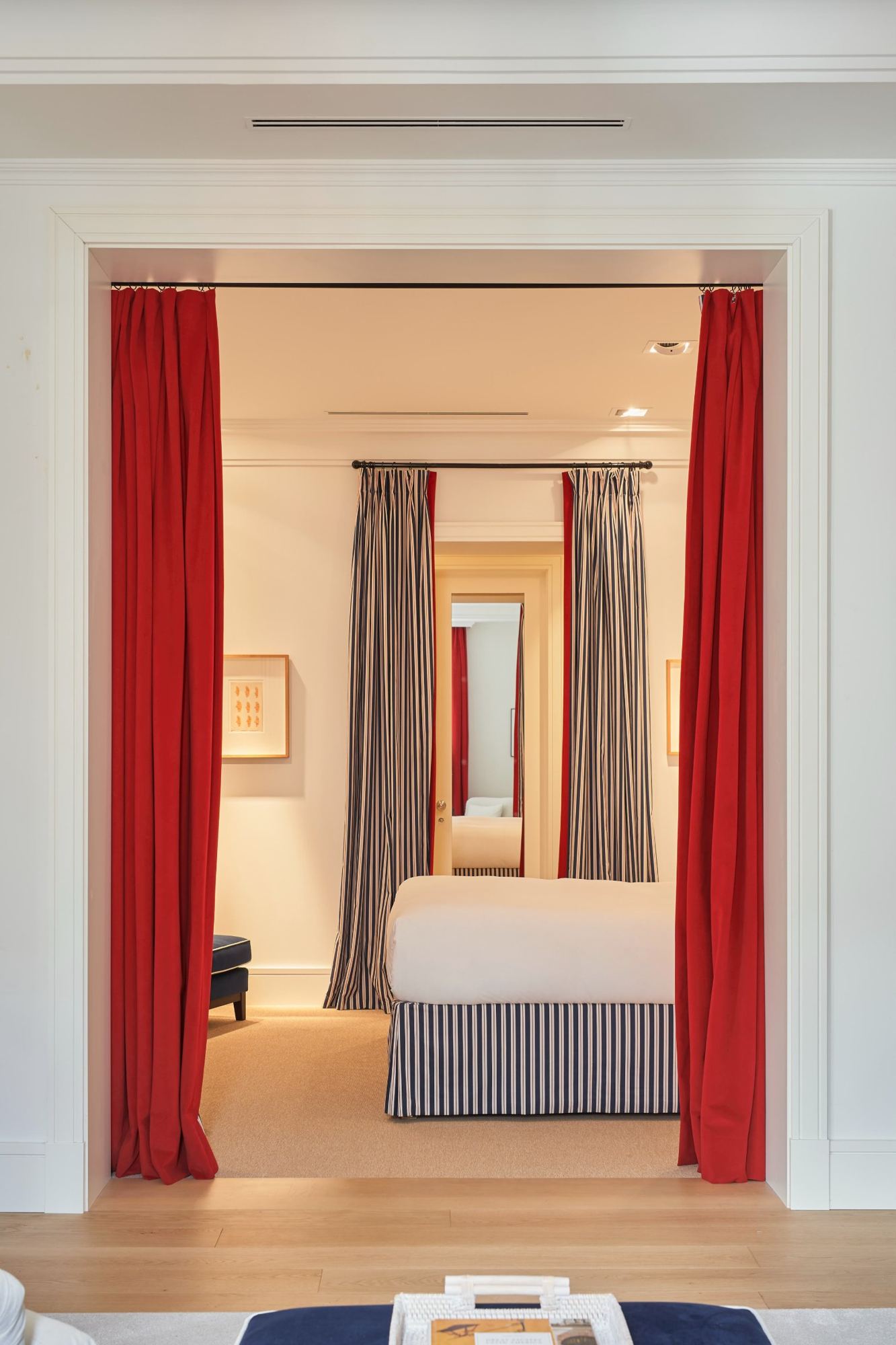 The master bedroom framed by red velvet curtains, seen from the sitting room