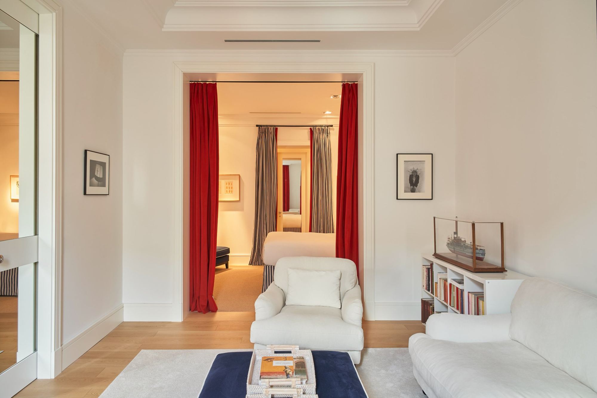 The master suite sitting room opening onto the bedroom through red curtains