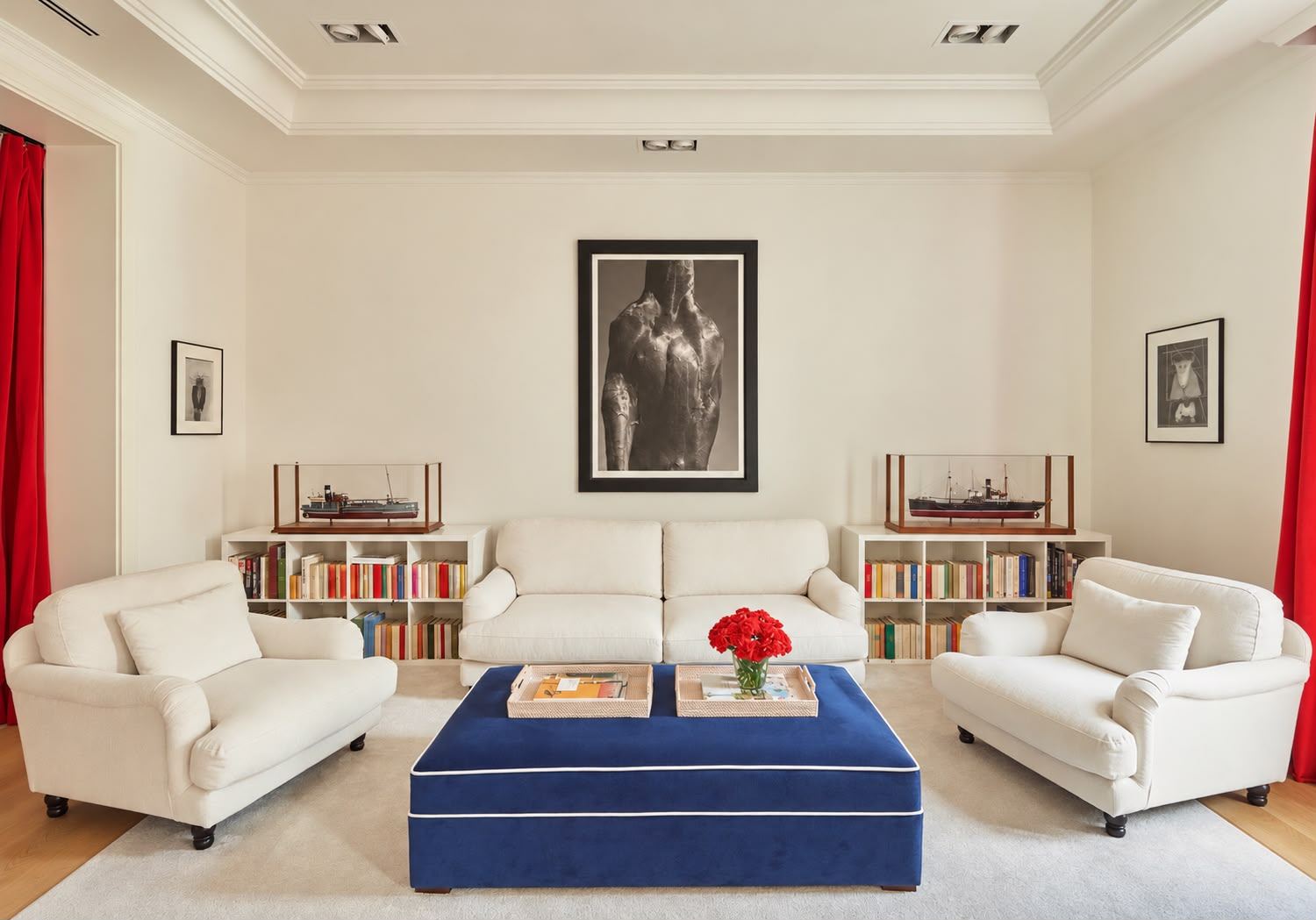 Master suite sitting room: white sofas, navy ottoman, bookcases and ship models