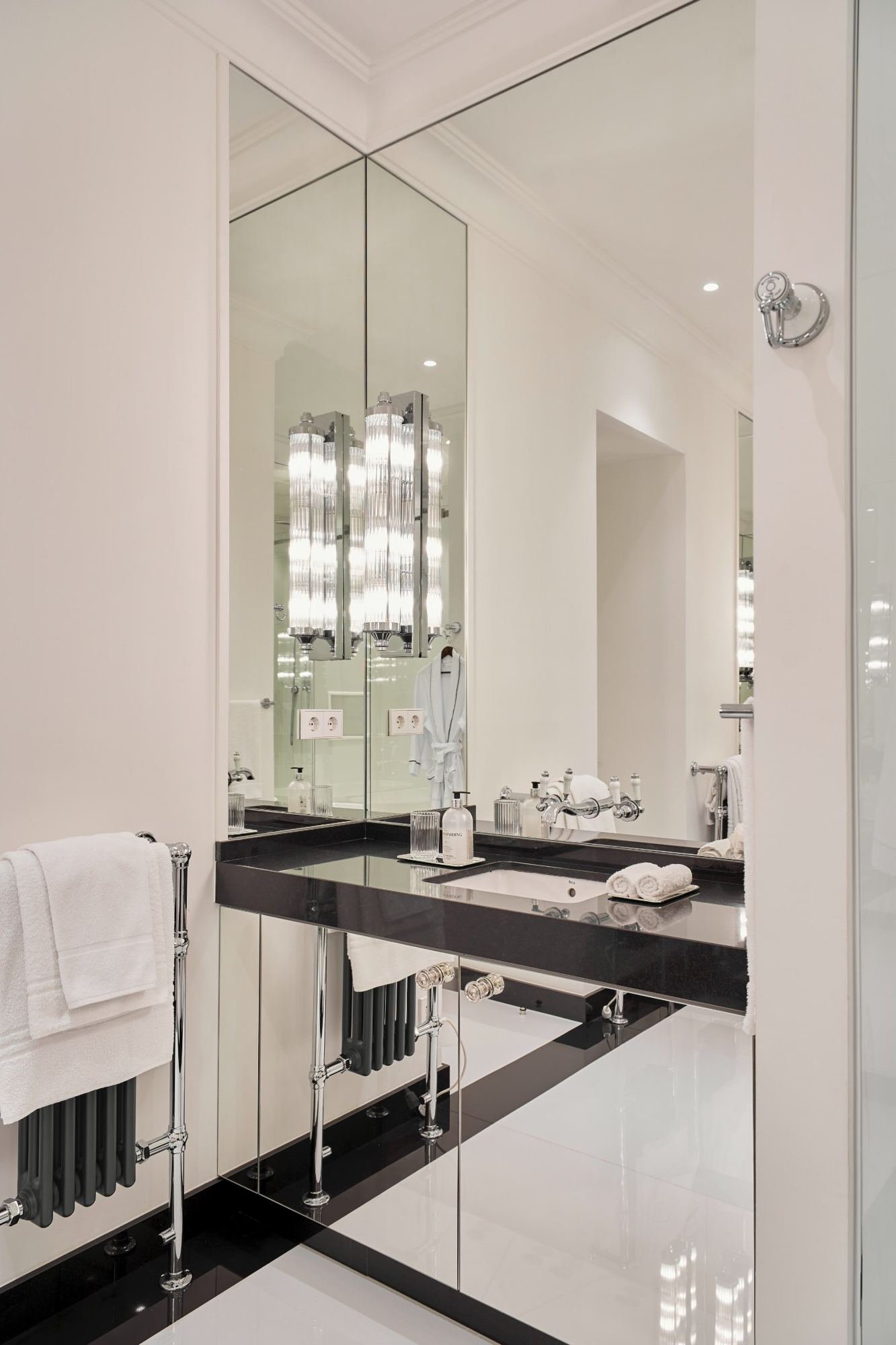 Master bath vanity with black stone top, mirrored panels and glass sconces