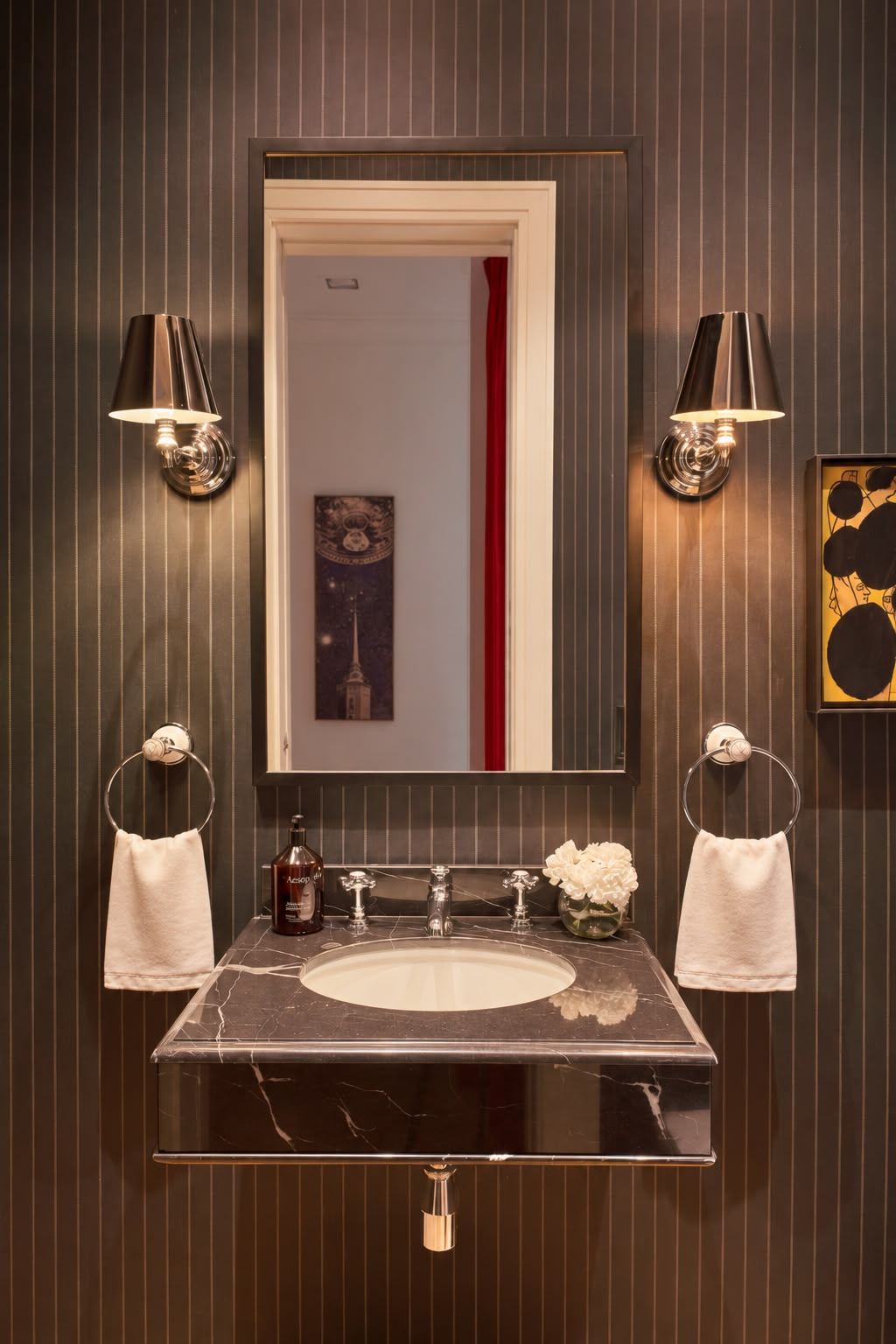 Powder room with pinstripe walls, nickel sconces and black marble basin
