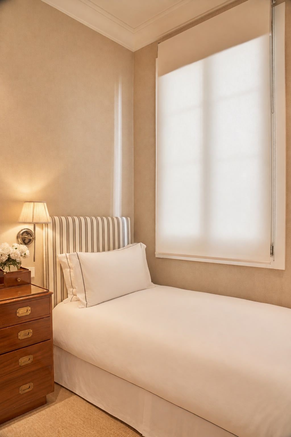 Single room with striped headboard and mahogany campaign chest