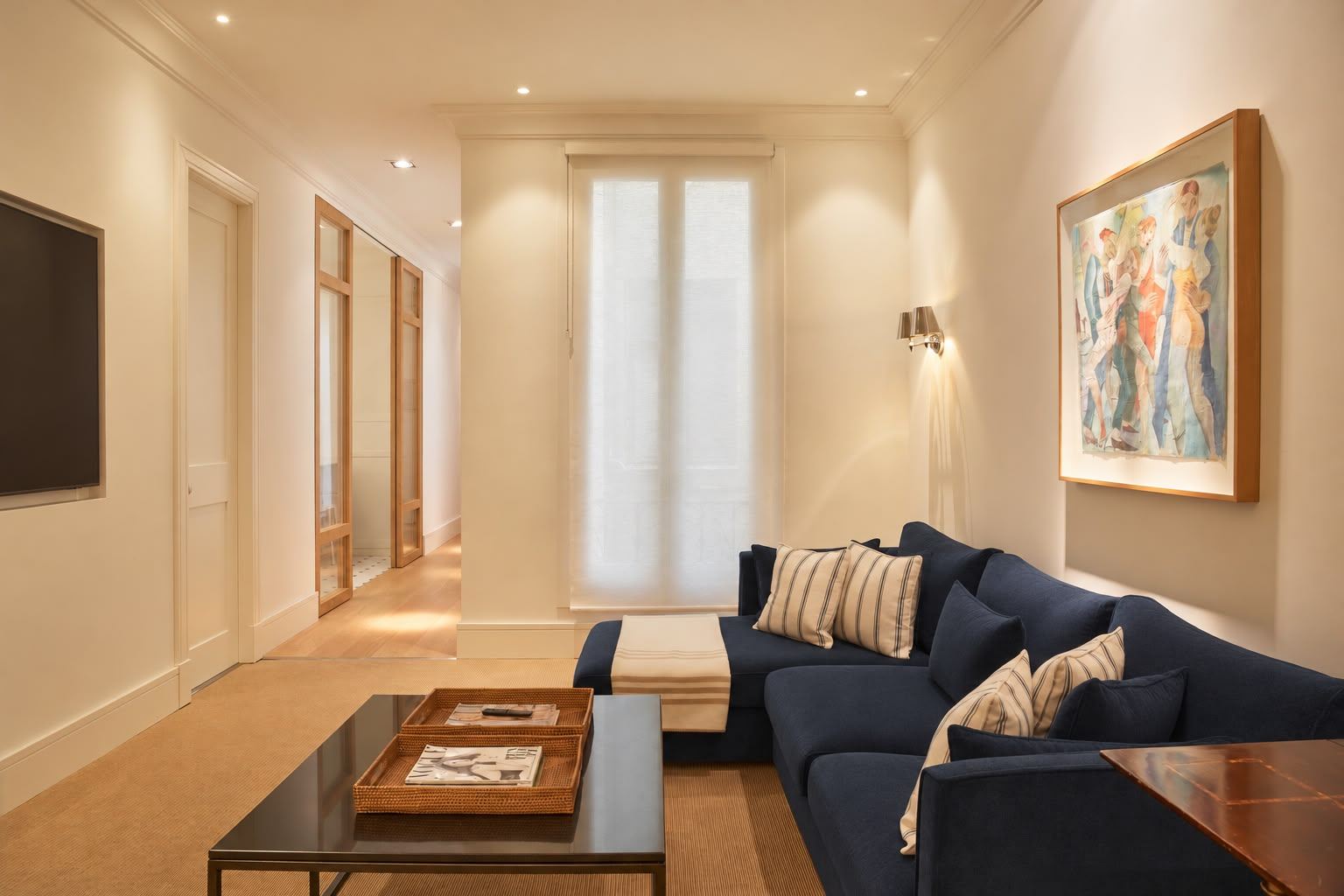 TV room with navy corner sofa, striped cushions and framed painting